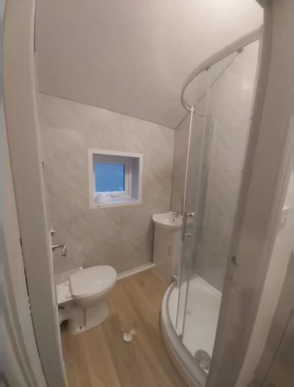 A finished bathroom with a quadrant shower, new WC and a wood effect floor