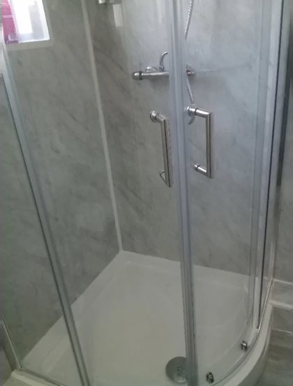 A quadrant shower enclosure finished in marble effect panelling