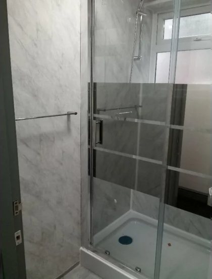 A shower over the bath with a glass screen and panelled walls