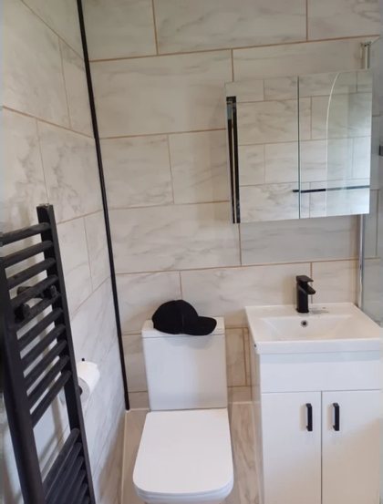 A bathroom with a heated towel rail, WC and vanity unit in place