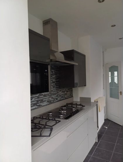 A kitchen with the hob, extractor and splashback finished