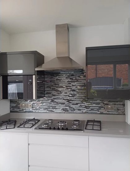 A kitchen with a stainless chimney extractor over the hob