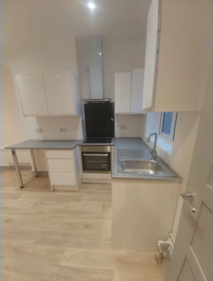 A compact kitchen fitted with an oven, sink and new flooring