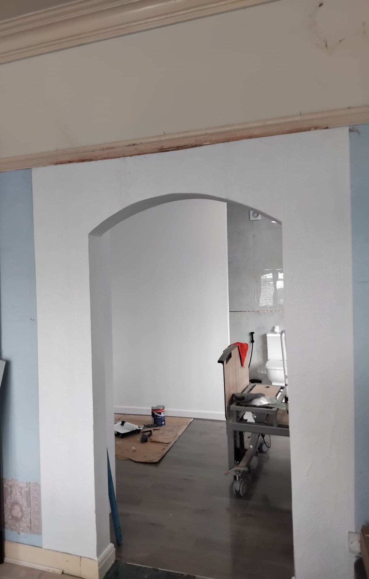 A new arched opening formed between a room and a ground floor wet room, plastered and painted