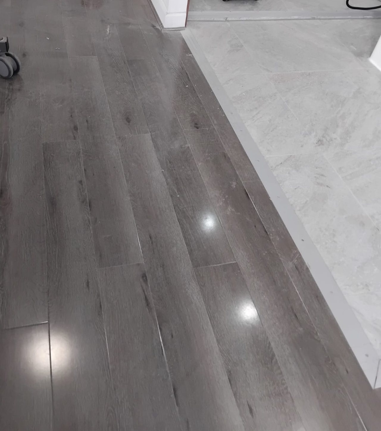 Wood effect laminate meeting a tiled wet room floor on a flush, level threshold