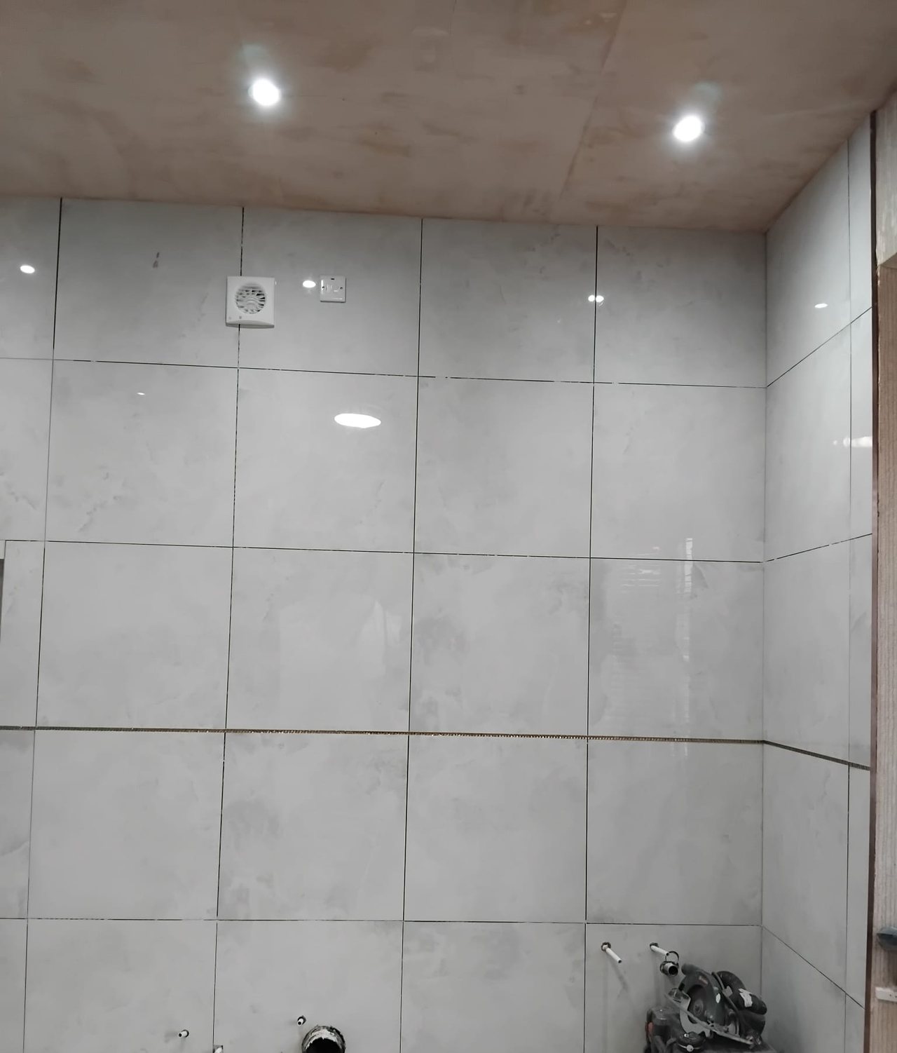 Large format wall tiles going up over the first fix pipework and waste