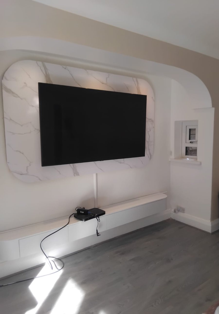 A finished media wall: backlit marble effect panel, wall hung television and a long floating unit
