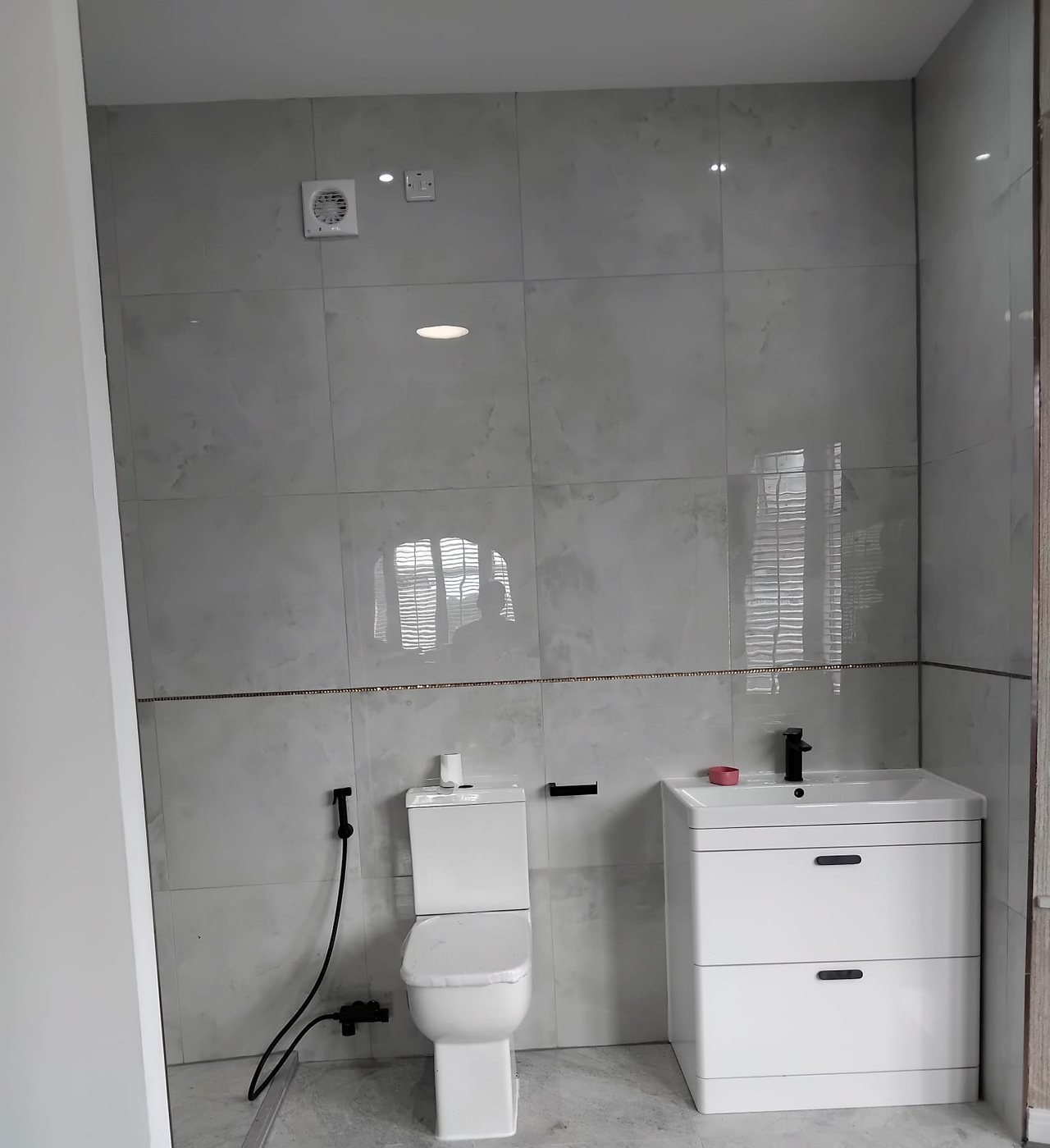 A finished bathroom with a close coupled WC, a two drawer vanity unit and black fittings