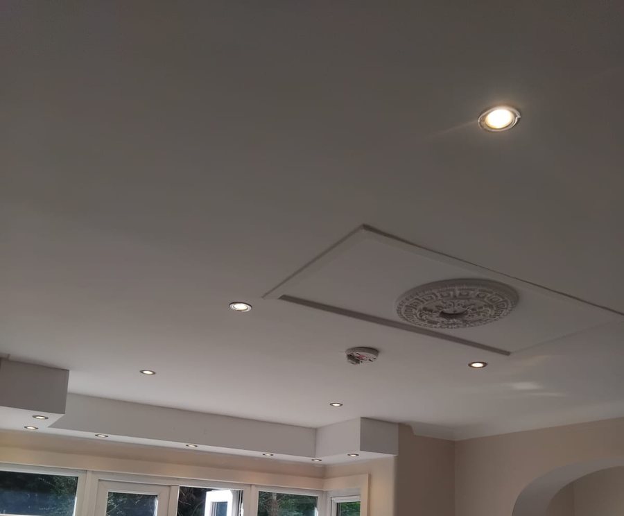 A living room ceiling with a recessed feature panel, ceiling rose and downlights